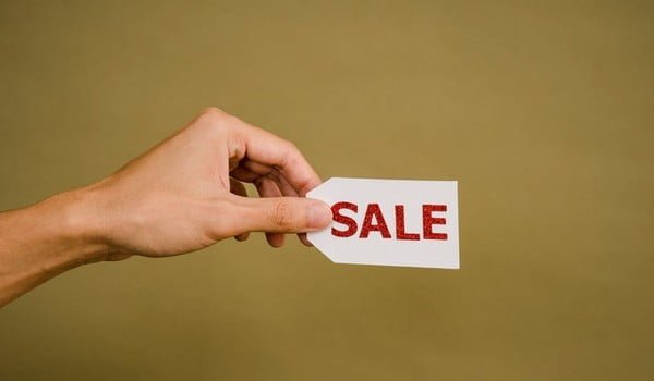 A persons hand with a sale tag